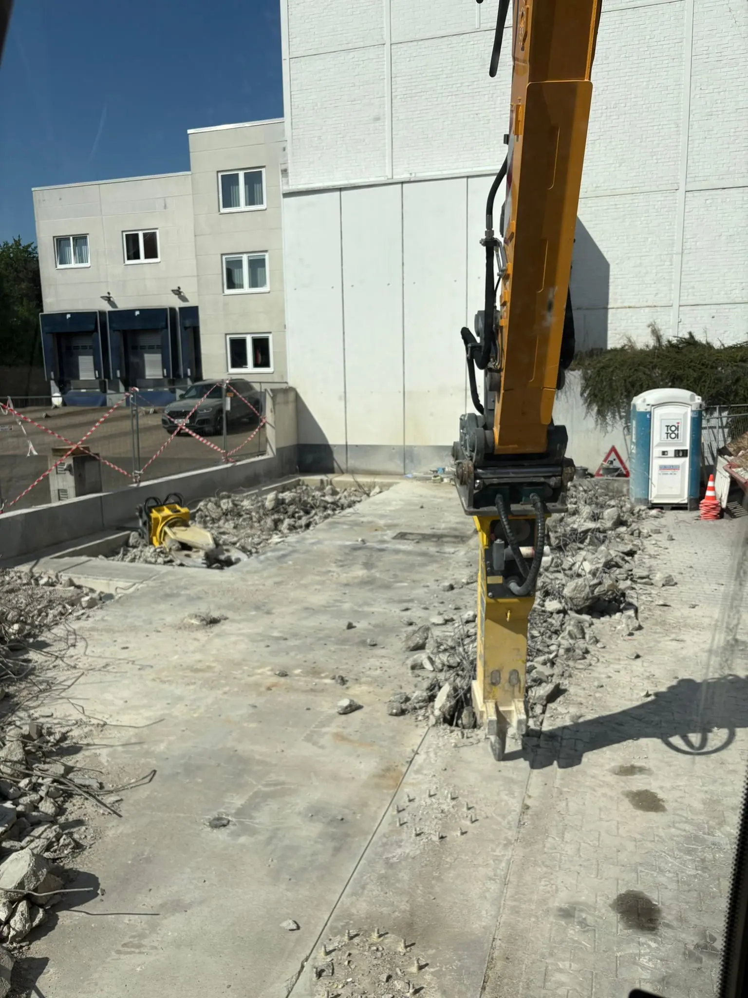 Bagger mit Anbaugerät beim kontrollierten Abbruch einer Betonfläche